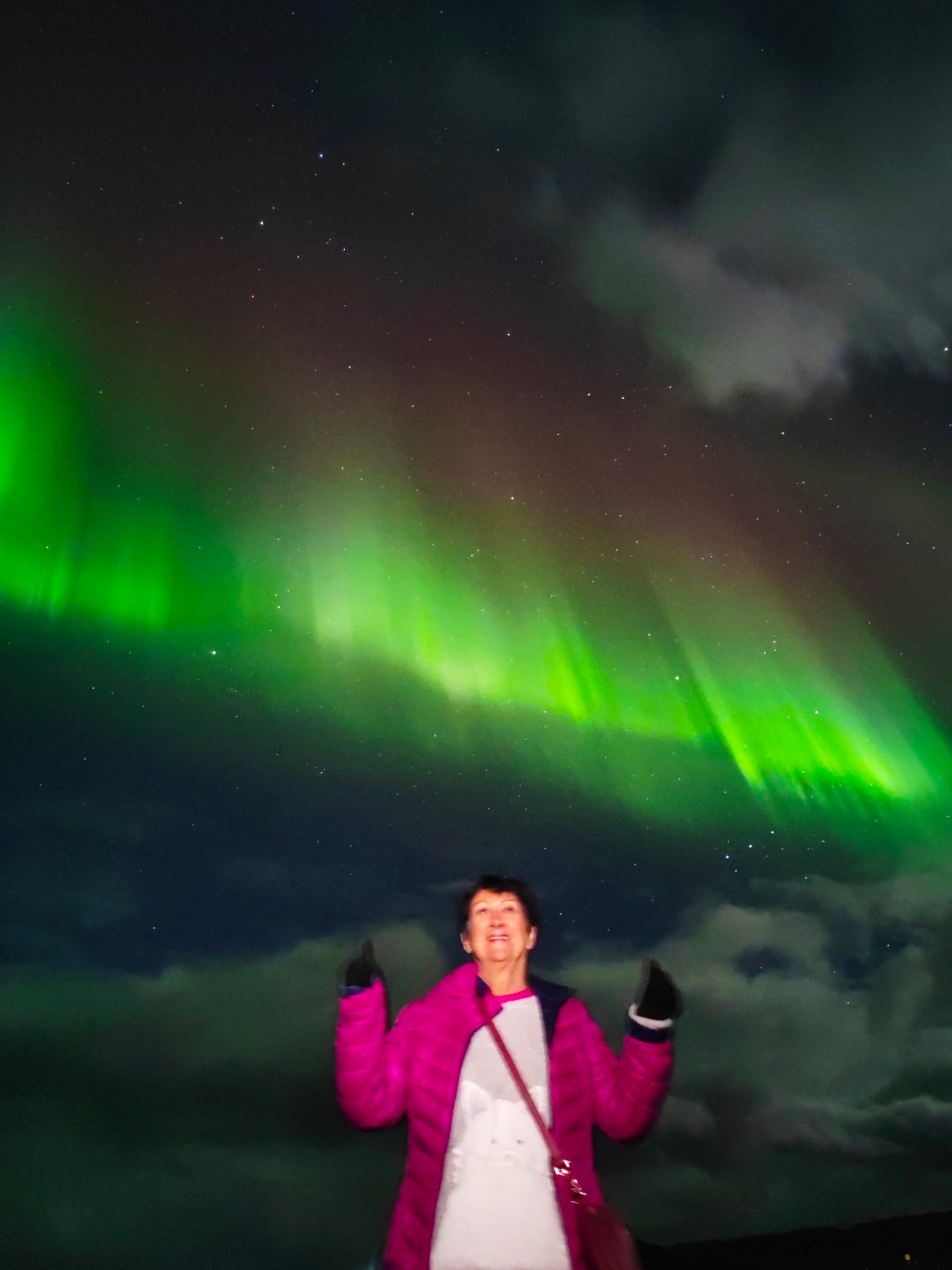 Viajera bajo cortina de auroras boreales en Islandia