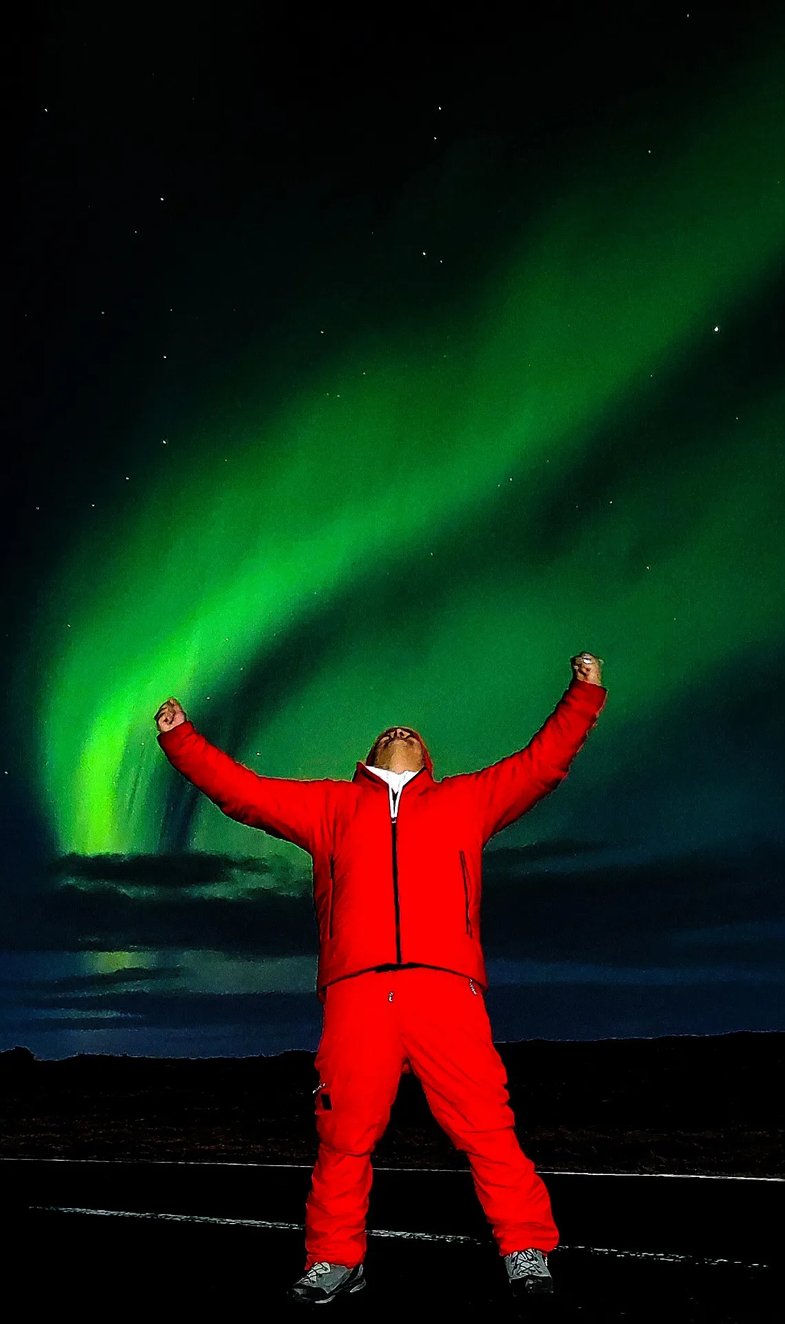 Viajero con bandera de Islandia bajo aurora boreal